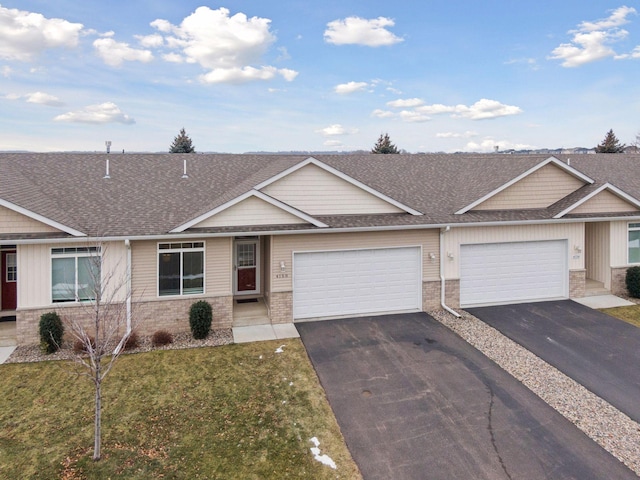 view of front of property with an attached garage, a shingled roof, brick siding, driveway, and a front yard