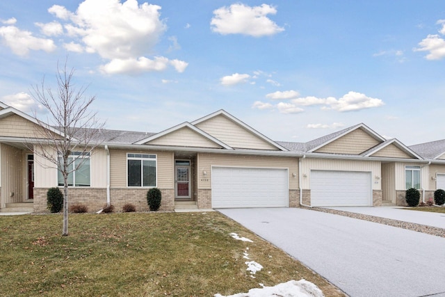 view of front of home featuring an attached garage, concrete driveway, brick siding, and a front yard