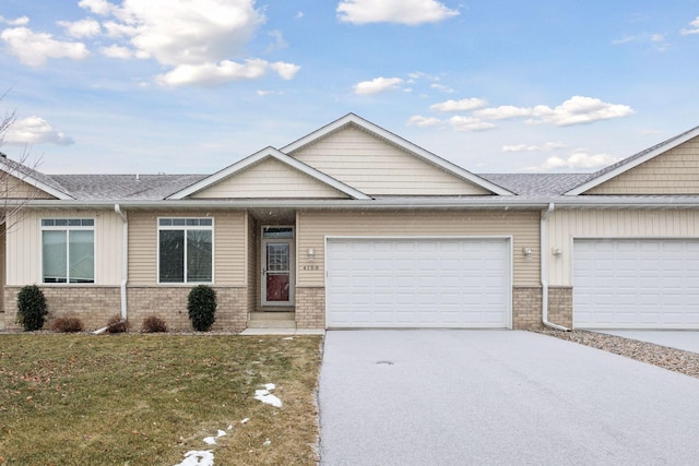 view of front of house with brick siding, roof with shingles, an attached garage, driveway, and a front lawn