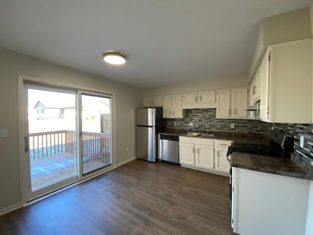 kitchen with white cabinets, backsplash, appliances with stainless steel finishes, and dark wood-type flooring