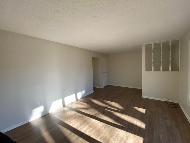 unfurnished room with dark wood-type flooring and a textured ceiling