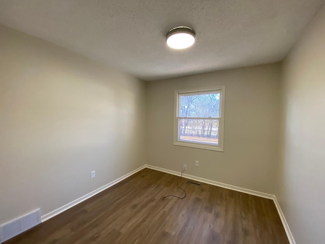 spare room with dark hardwood / wood-style floors and a textured ceiling