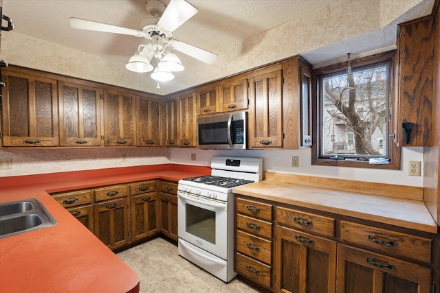 kitchen with white range with gas cooktop, sink, a textured ceiling, and ceiling fan