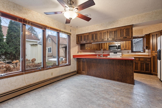 kitchen featuring sink, ceiling fan, appliances with stainless steel finishes, a baseboard radiator, and kitchen peninsula