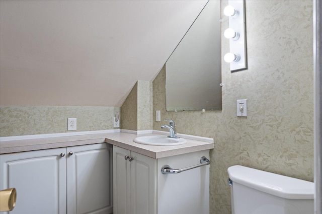 bathroom with lofted ceiling, vanity, and toilet