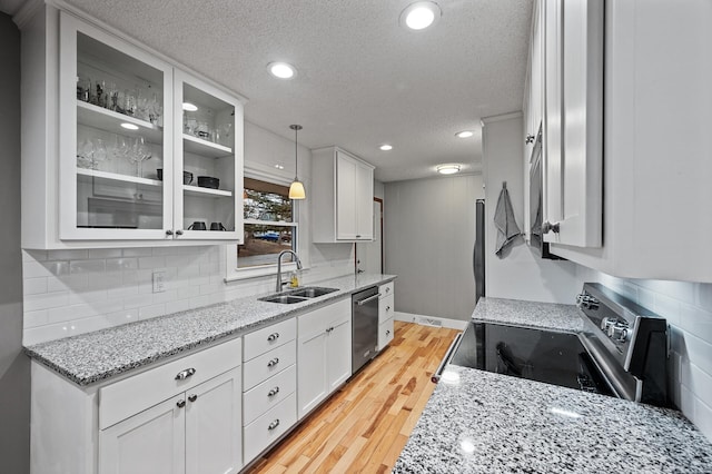 kitchen featuring light wood-type flooring, white cabinetry, stainless steel appliances, and a sink