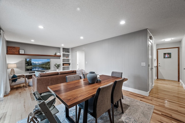 dining space with light wood-style floors, baseboards, a textured ceiling, and recessed lighting