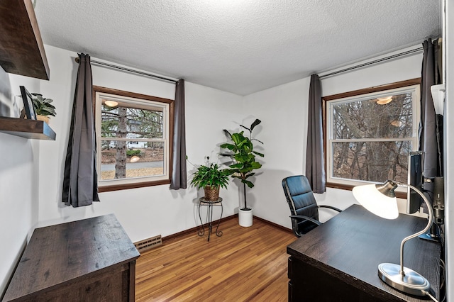 office area featuring baseboards, visible vents, a textured ceiling, and light wood finished floors