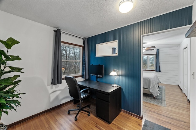 office area featuring a textured ceiling, baseboards, and wood finished floors