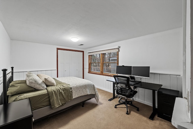 bedroom featuring a wainscoted wall, a closet, and carpet flooring