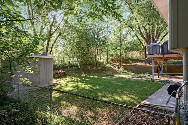 view of yard with an outbuilding, a shed, fence, and a deck