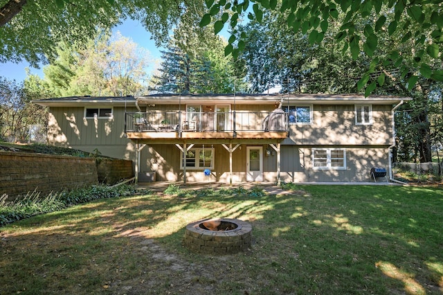 rear view of property featuring an outdoor fire pit, a lawn, and a deck