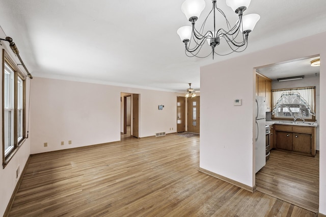 interior space with crown molding, sink, ceiling fan with notable chandelier, and light wood-type flooring