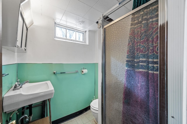 bathroom featuring toilet and a shower with shower door