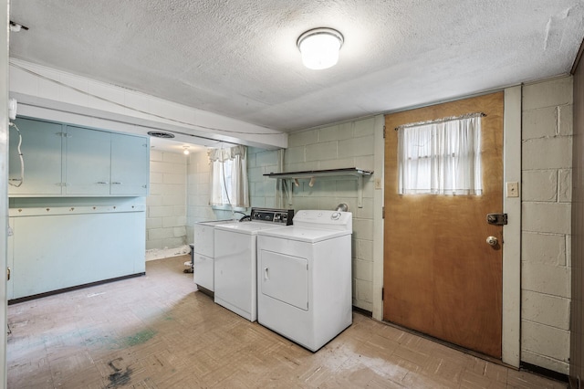 clothes washing area featuring cabinets, independent washer and dryer, light parquet flooring, and a textured ceiling