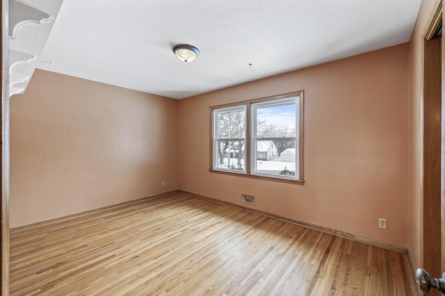 spare room featuring a textured ceiling and light wood-type flooring