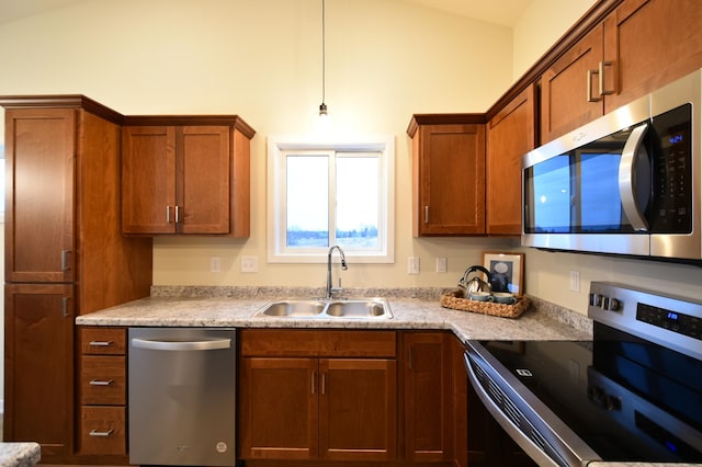 kitchen with light stone counters, sink, decorative light fixtures, and appliances with stainless steel finishes