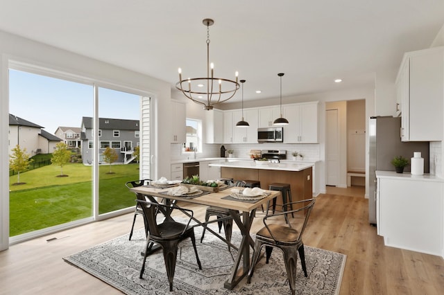 dining room featuring light wood-type flooring, sink, and a chandelier