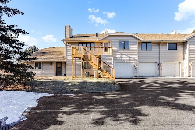 rear view of property with a wooden deck and a garage