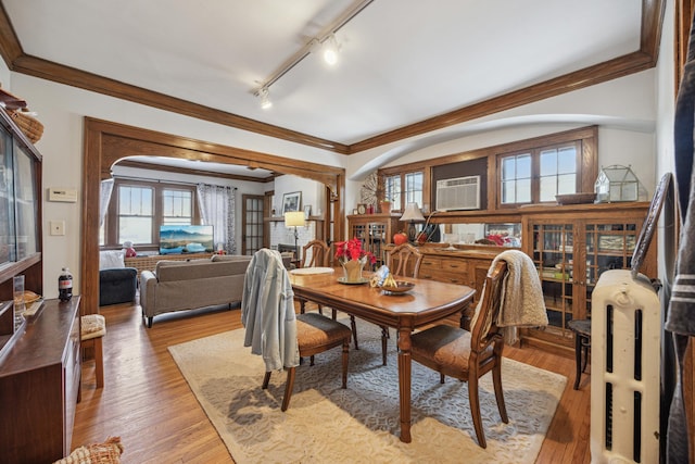 dining area with track lighting, a wall unit AC, crown molding, and light hardwood / wood-style flooring