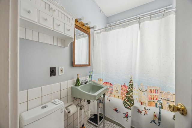 bathroom featuring toilet, a shower with shower curtain, tile walls, and sink