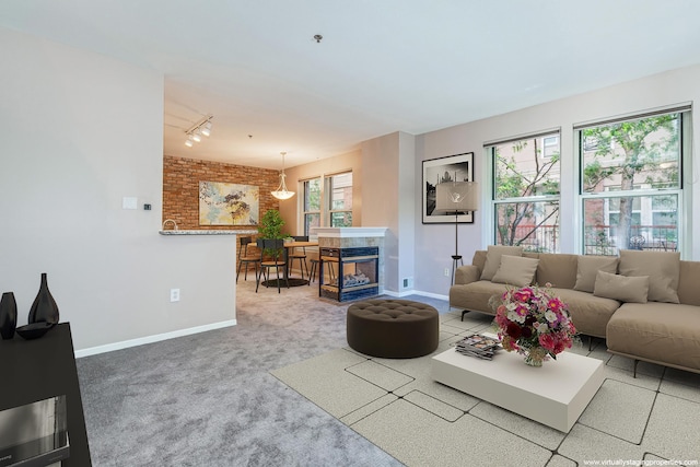 living room featuring carpet, a multi sided fireplace, brick wall, and track lighting