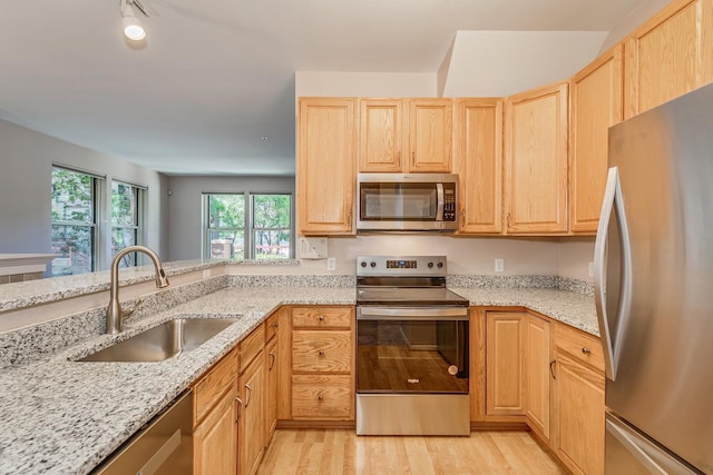 kitchen with light stone counters, light brown cabinetry, sink, and appliances with stainless steel finishes