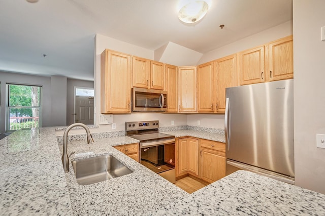 kitchen with light stone countertops, sink, light brown cabinets, kitchen peninsula, and appliances with stainless steel finishes