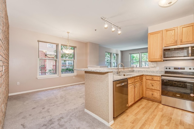 kitchen with light brown cabinets, kitchen peninsula, sink, and appliances with stainless steel finishes