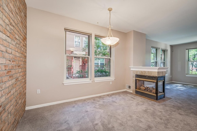 unfurnished living room with a multi sided fireplace and carpet