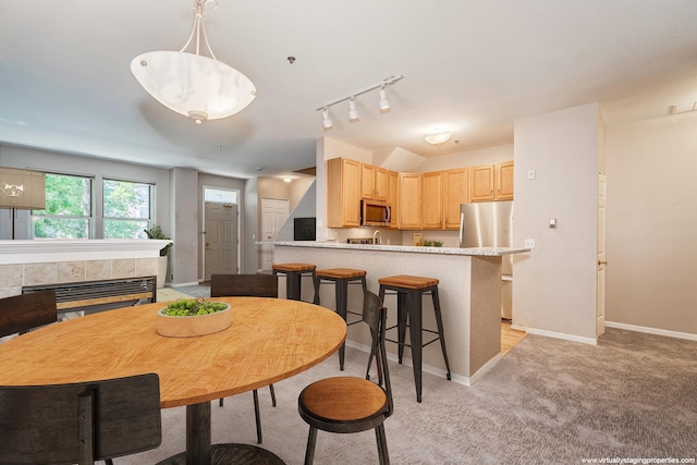 dining room with light colored carpet, rail lighting, and a tiled fireplace