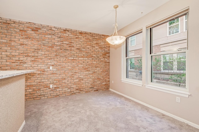 carpeted spare room featuring brick wall