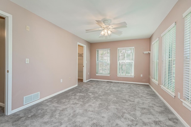 unfurnished bedroom with a closet, a spacious closet, ceiling fan, and light colored carpet