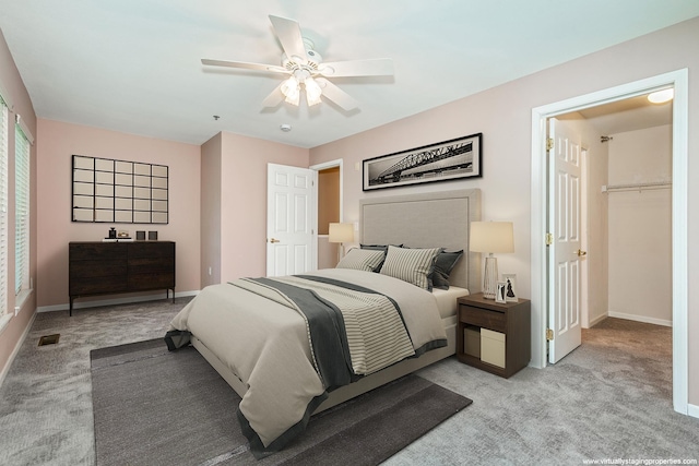 carpeted bedroom featuring a closet, a spacious closet, and ceiling fan