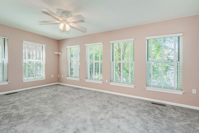 carpeted empty room featuring ceiling fan and a wealth of natural light