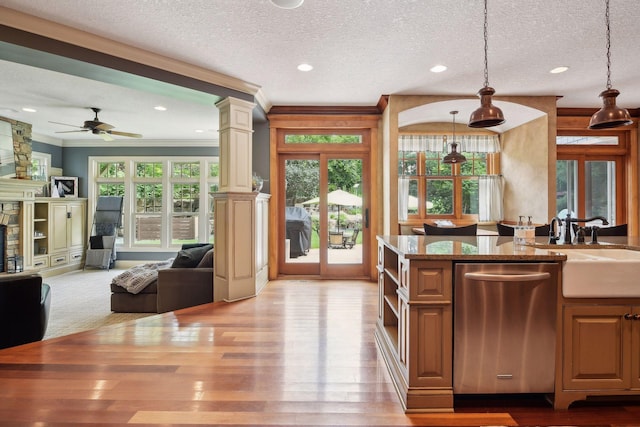 kitchen with pendant lighting, stainless steel dishwasher, a textured ceiling, and decorative columns