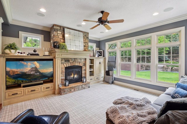 living room featuring a textured ceiling, a stone fireplace, ceiling fan, and ornamental molding