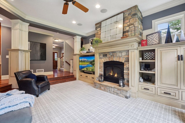 living room featuring carpet flooring, a stone fireplace, ceiling fan, and ornamental molding