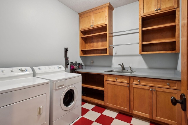 clothes washing area with cabinets, a textured ceiling, separate washer and dryer, and sink