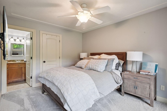 bedroom featuring light carpet, ensuite bathroom, and ceiling fan