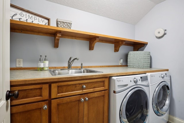 clothes washing area featuring separate washer and dryer, sink, cabinets, and a textured ceiling