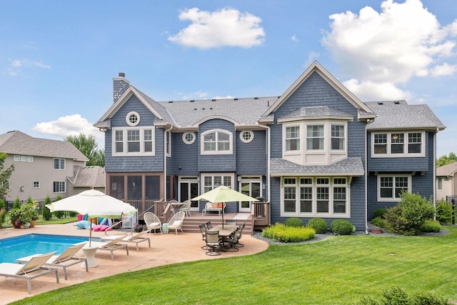 back of house with a sunroom, a yard, a pool side deck, and a patio