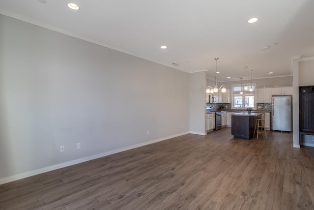 unfurnished living room with sink, dark hardwood / wood-style floors, and ornamental molding