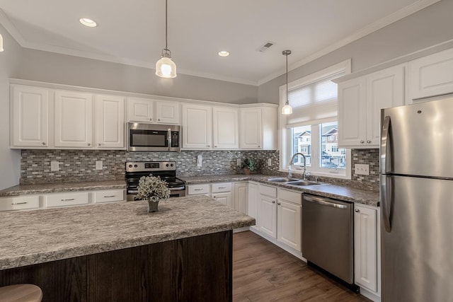 kitchen featuring appliances with stainless steel finishes, white cabinetry, hanging light fixtures, and sink