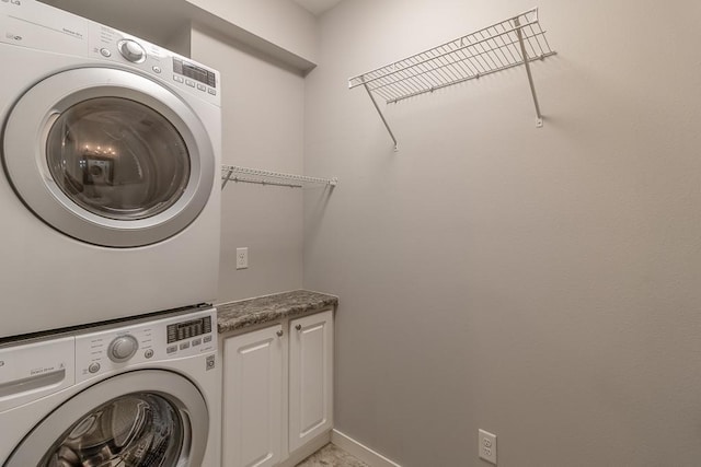 washroom featuring cabinets and stacked washing maching and dryer