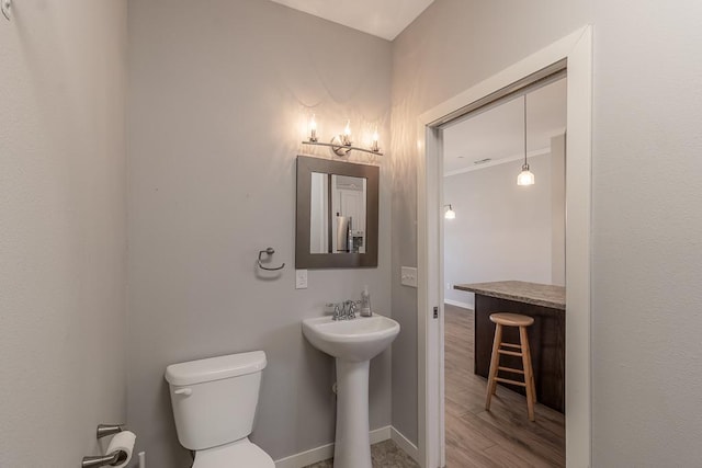 bathroom with hardwood / wood-style flooring, sink, crown molding, and toilet