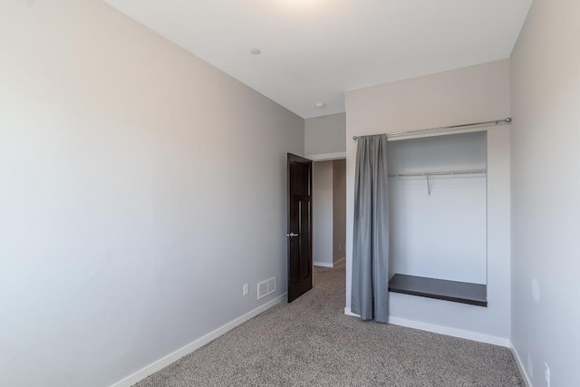 unfurnished bedroom featuring light carpet and a closet