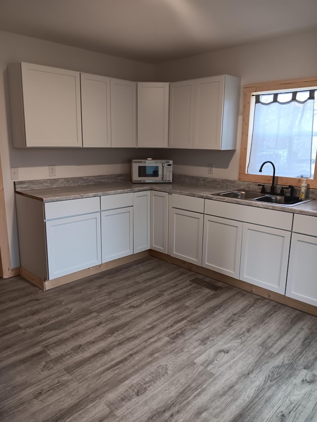 kitchen featuring white cabinetry, sink, and light hardwood / wood-style flooring