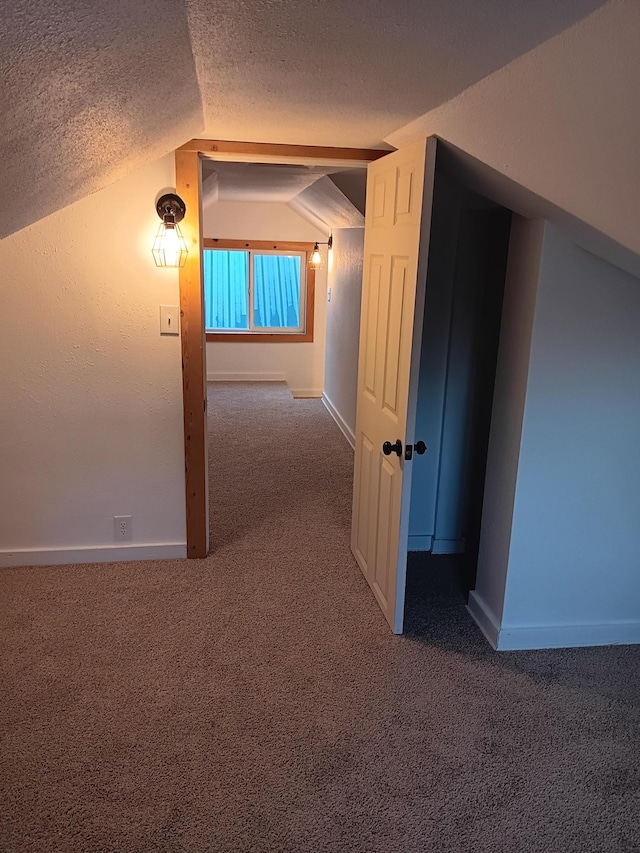 hall featuring vaulted ceiling, carpet floors, and a textured ceiling