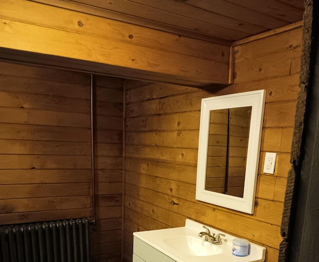 bathroom with vanity, radiator heating unit, and wood walls